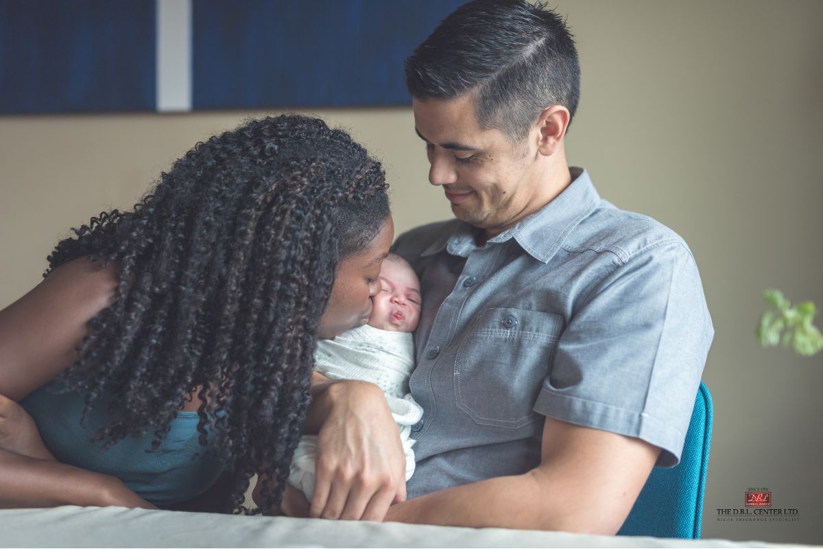 A father is holding an infant while the mother kisses the baby's cheek - family bonding at its best.