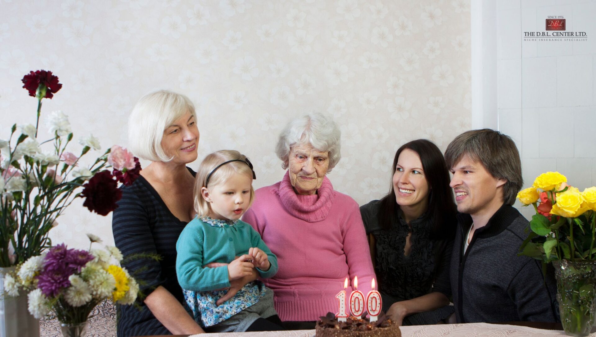 Sandwich generation caregiving Four generations at a table, celebrating a mother's 100th birthday.