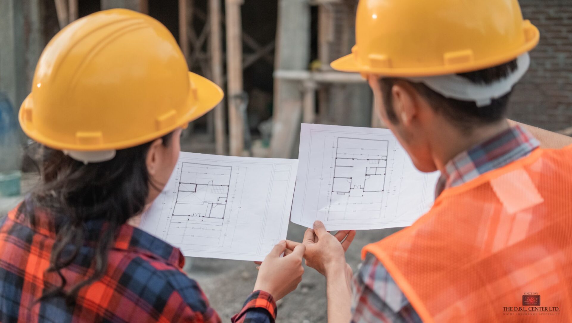 government contractors on a jobsite – DBL Center A man and a woman in hard hats on a job site, reading blueprints. Can only see the backs of their heads.