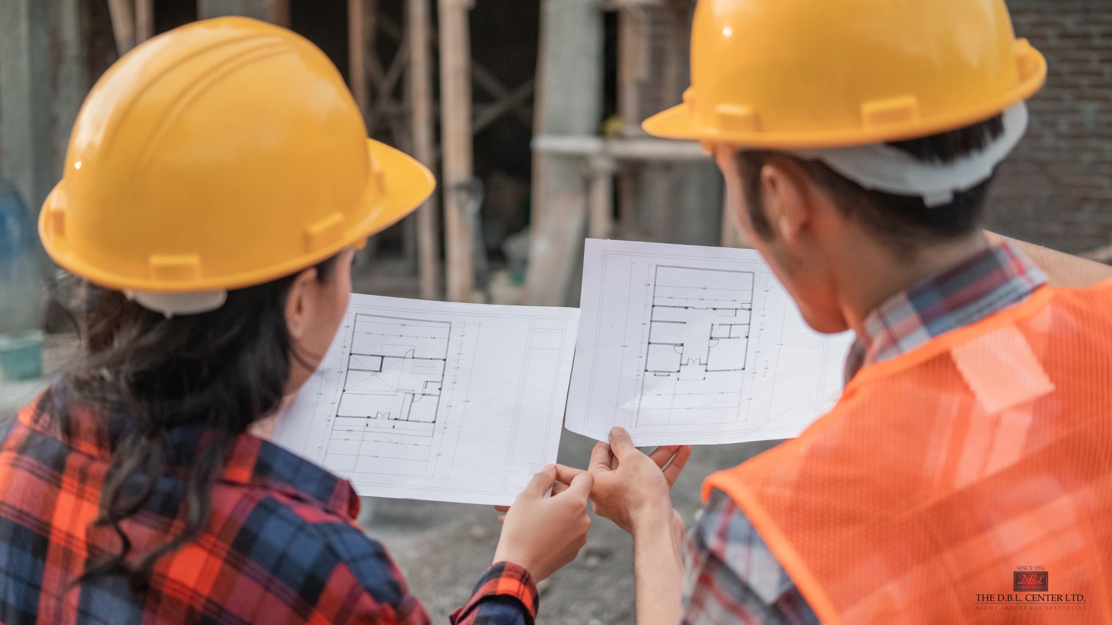 government contractors on a jobsite - DBL Center A man and a woman in hard hats on a job site, reading blueprints. Can only see the backs of their heads.